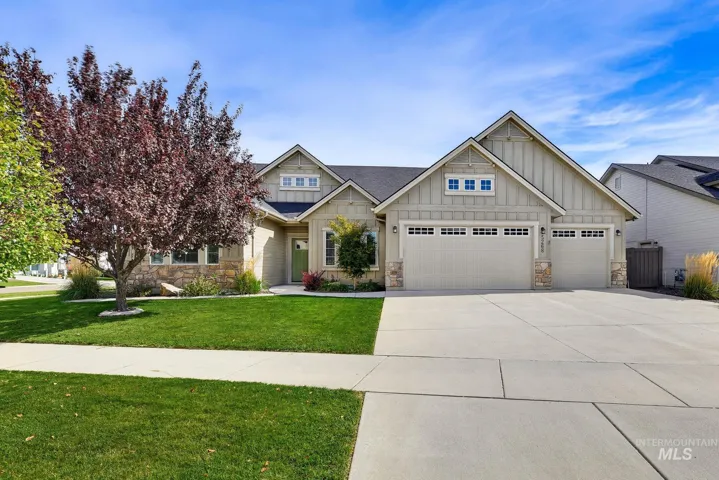 Gable-style roofline with board and batten siding, stone facade accents, two-car garage, concrete driveway, and a vibrant green lawn