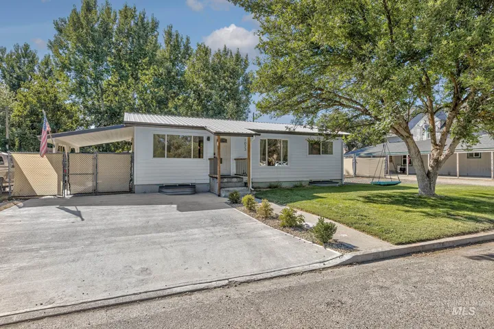 Bungalow with a metal roof, concrete driveway, a carport, and a gate