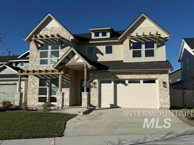 Two-story residence featuring stone veneer siding, decorative wooden pergolas, a gabled roofline, multi-pane windows, and an attached two-car garage
