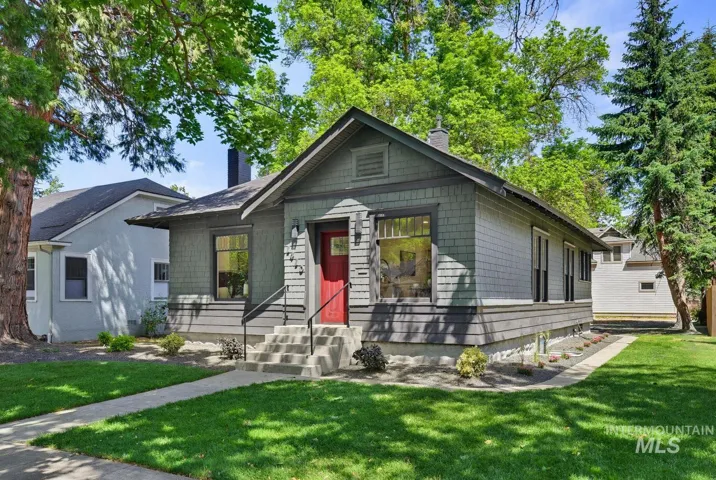 Craftsman-style exterior featuring gray shake siding, a red entry door, and a covered front porch with dark railings