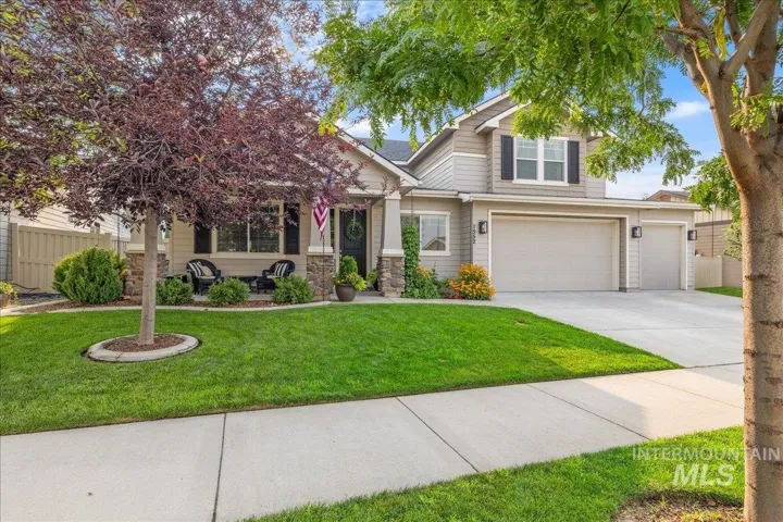 Contemporary two-story residence with a covered front porch featuring stone accents, a multi-car garage, and a manicured lawn with mature landscaping