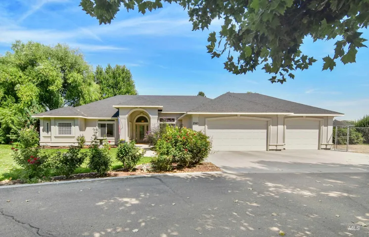 Stucco exterior with an arched entry, a dark shingle roof, and an attached three-car garage