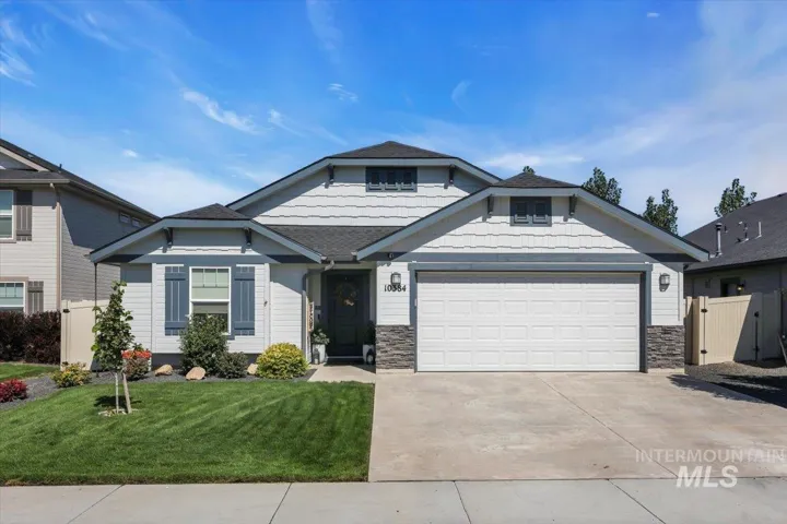 Front exterior featuring white siding, dark gray roof, two-car garage, and stone accents