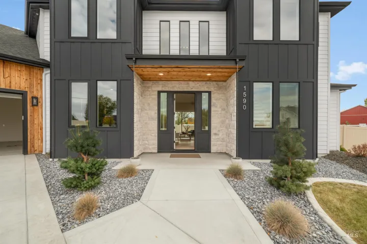 Modern exterior featuring high-contrast vertical siding, stone masonry accents, wood-paneled porch ceiling, and a concrete walkway