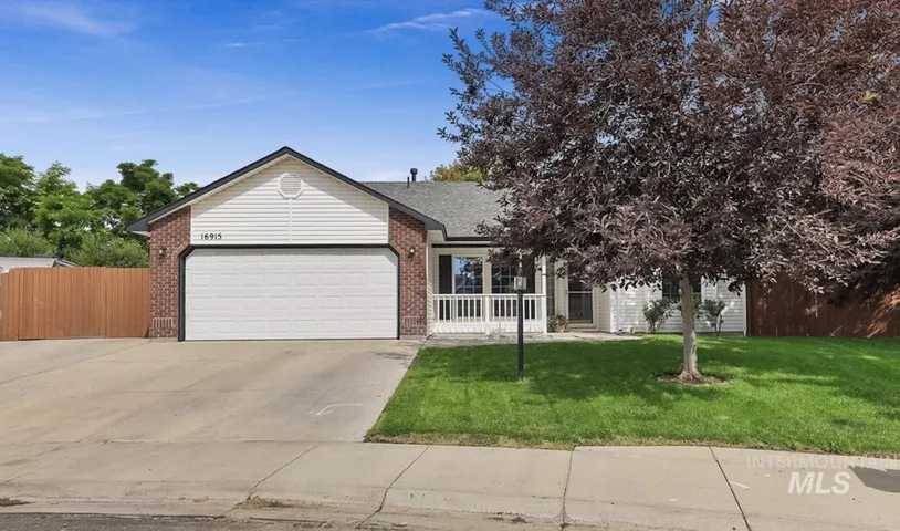 Traditional-style home featuring a brick and siding exterior, an attached two-car garage, and a covered front porch with white railings