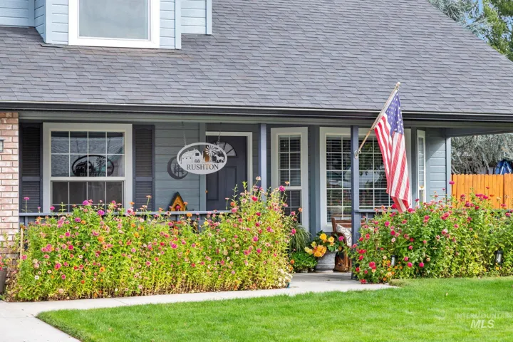 Blue horizontal lap siding exterior featuring a covered front porch, asphalt shingle roof, brick accent wall, and multi-paned windows