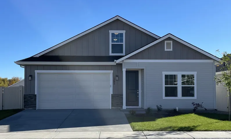 View of front of house featuring driveway, board and batten siding, and stone siding
