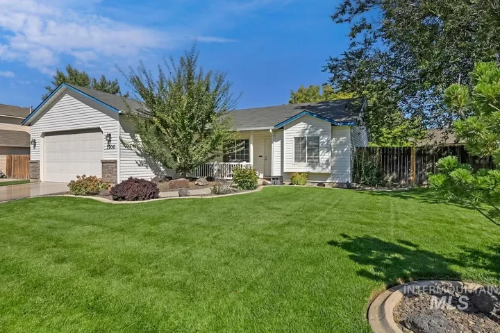 White siding exterior with a two-car garage, covered porch, and landscaped front yard