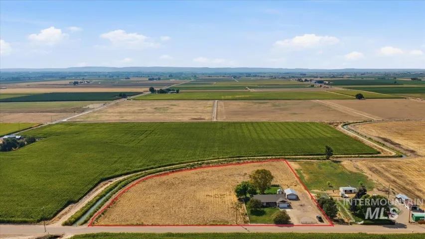 Expansive property featuring a single-story residence, multiple outbuildings, and a large open lot