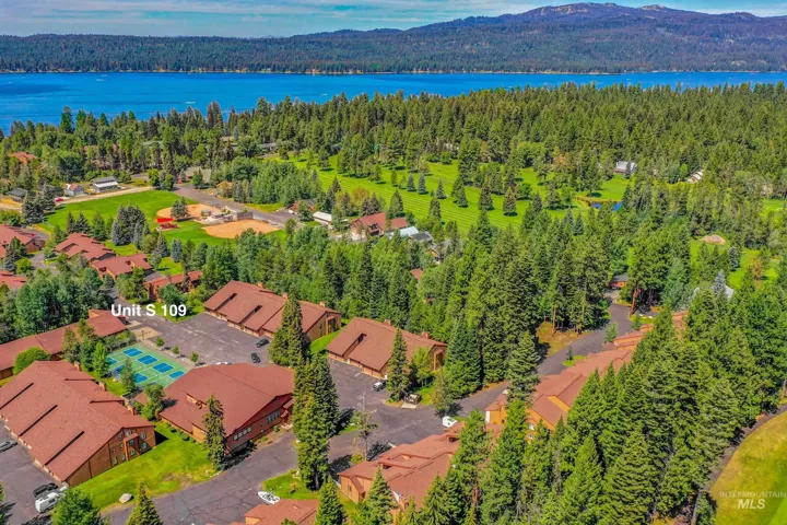Aerial representation of a residential complex with red-tiled roofs, surrounded by dense evergreen trees and manicured green spaces