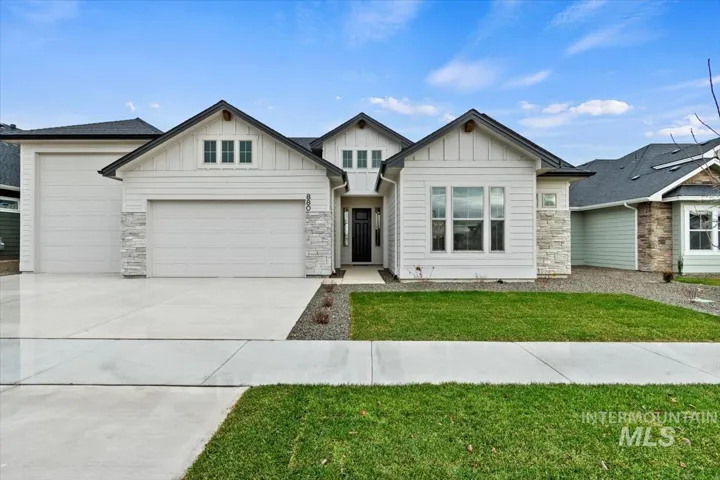 Craftsman-style house featuring board and batten siding, a front lawn, concrete driveway, and stone siding