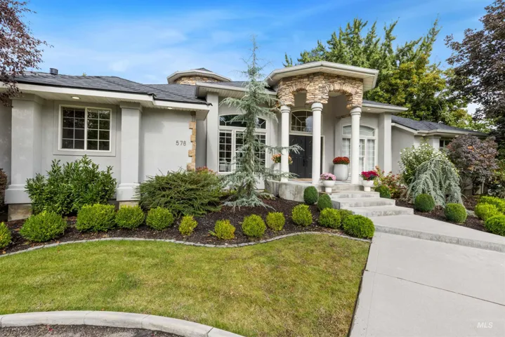 View of front facade featuring stucco siding, a front yard, and stone siding
