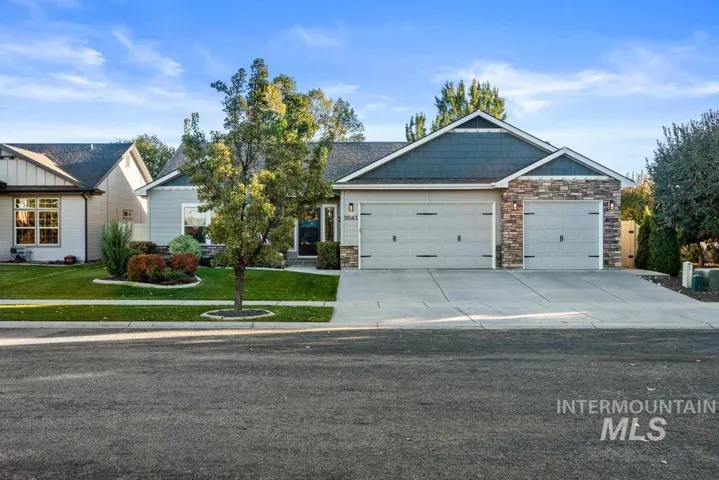 Single-story residence featuring horizontal lap siding, stone veneer accents, a triple-paneled garage door, and architectural shingle roofing
