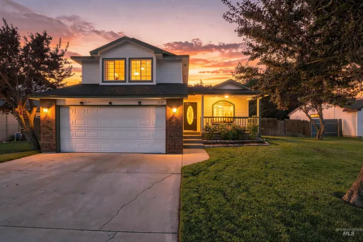 Two-story residence featuring a covered front porch, brick and siding exterior, attached garage, and a concrete driveway