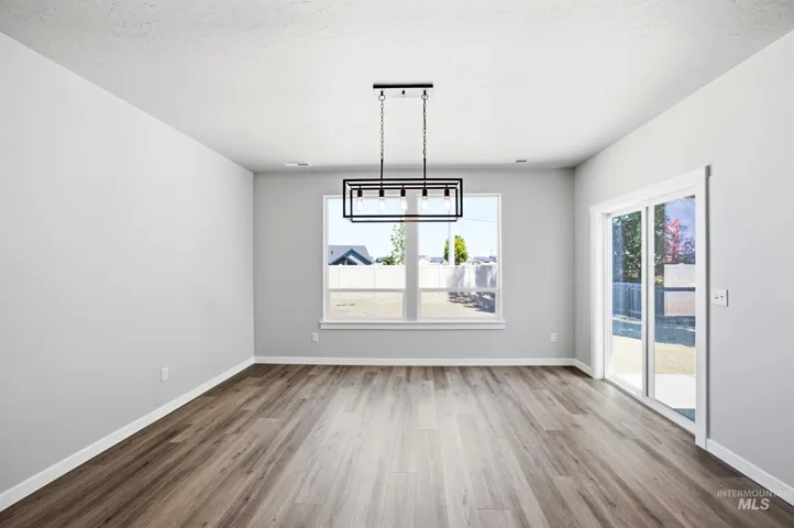 Wood-finish flooring, white trim, sliding glass door, white walls, and a contemporary chandelier