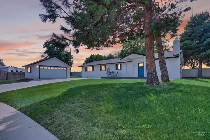 White exterior with black trim, a vibrant blue entry door, an attached garage, a detached garage, and a concrete driveway