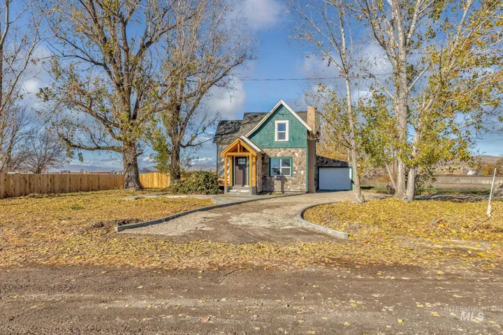 View of front of home with a garage, stone siding, driveway, and a chimney