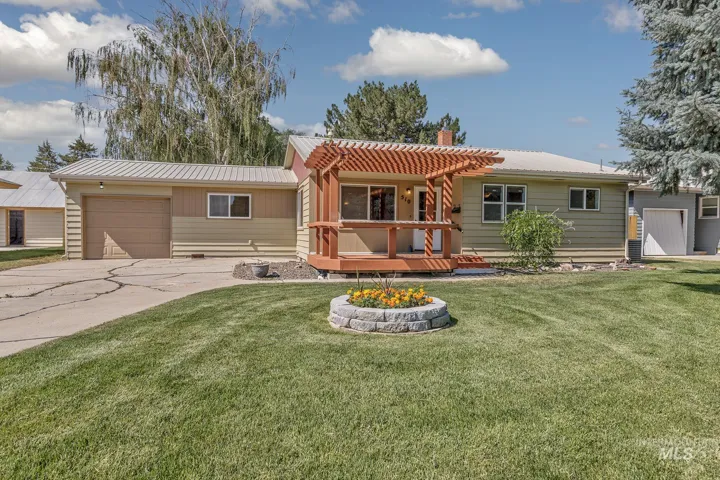 View of front of house with a fire pit, a chimney, a wooden deck, a garage, and driveway