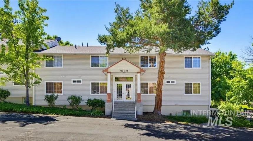 Multi-level building with light-toned siding and a covered front entrance