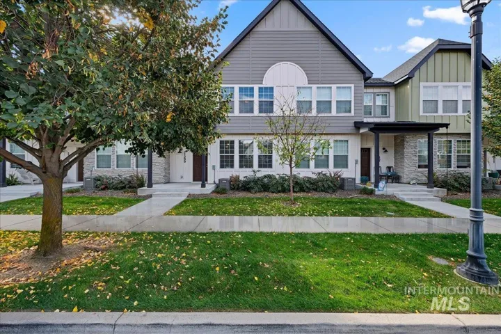 Multi-story townhouse exterior featuring horizontal lap siding, vertical board-and-batten accents, decorative stone veneer, and covered front entryways