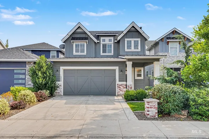 Contemporary home with board and batten siding, stone accents, a two-car garage, covered porch entry, and mature landscaping