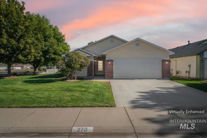 View of front of home with brick siding, driveway, an attached garage, and a yard