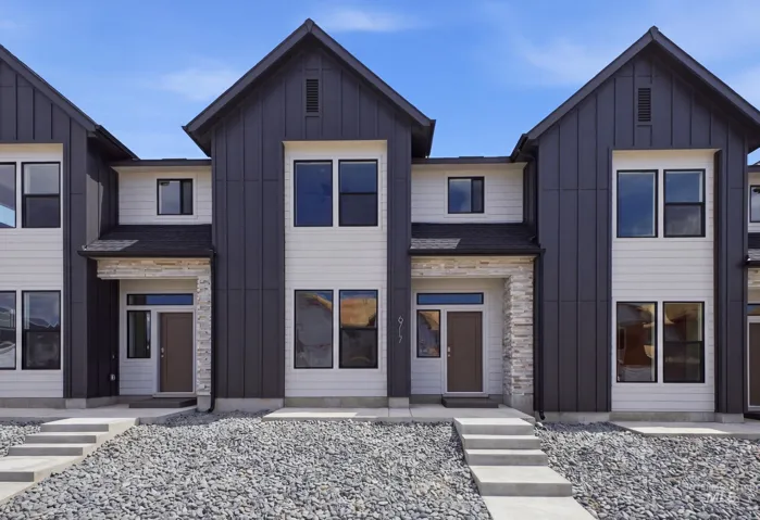 Contemporary townhome exterior featuring two levels, a dark gray standing seam metal facade, and light siding