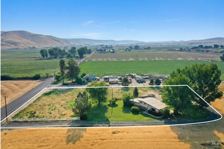 Expansive rural property featuring approximately 5+ acres of productive land with mature tree-lined perimeter, established pasture areas, and multiple outbuildings