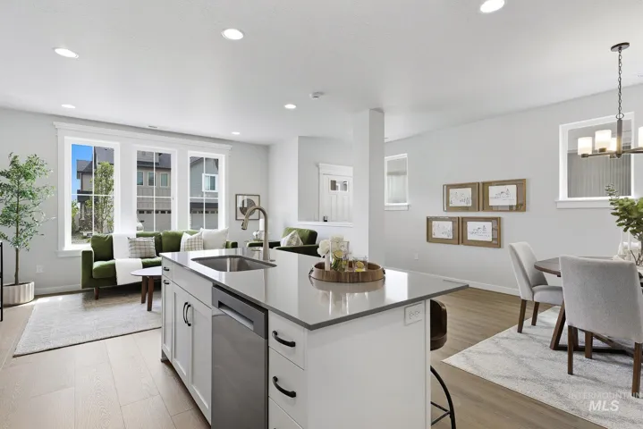 Open-concept kitchen featuring a center island with sink, stainless steel dishwasher, and light-toned countertops