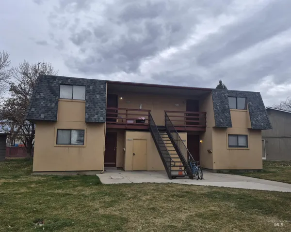 Front view featuring stucco siding, mansard roof, a lawn, and roof with shingles