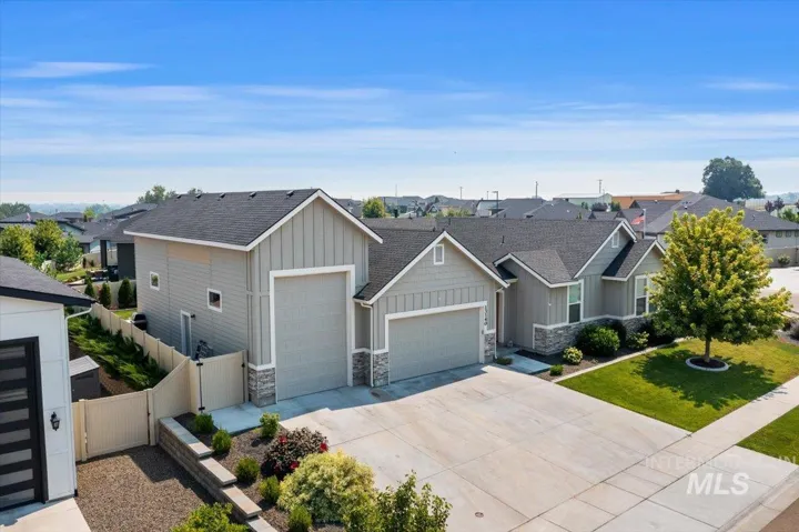 Exterior featuring light gray siding, stone veneer accents, an attached garage, a detached garage structure, and a concrete driveway
