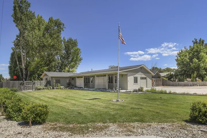 Ranch-style exterior with a low-pitch roofline, light-colored siding, and a prominent flagpole