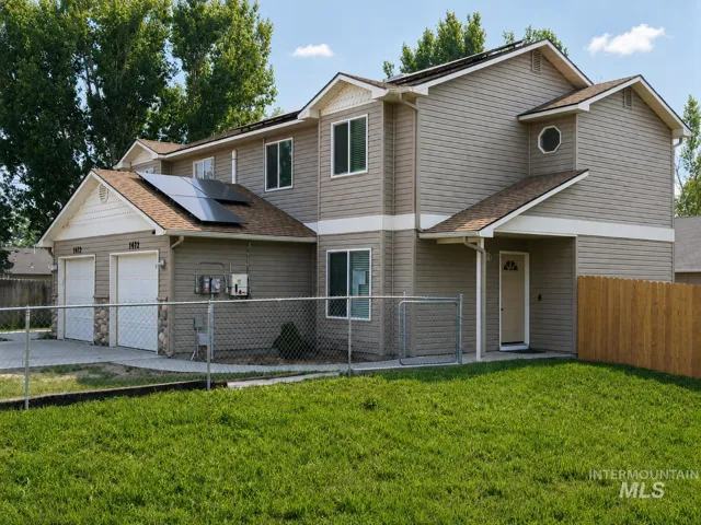 Contemporary exterior featuring horizontal siding, a double garage with stone accents, solar panels, a chain-link fence, and a wooden privacy fence