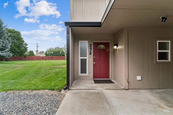 Red entry door with an arched transom window, covered porch, and exterior wall lantern