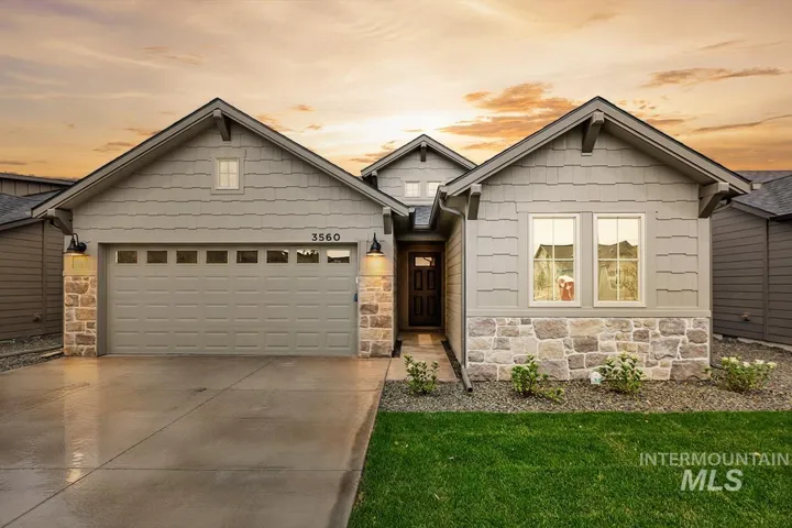 Craftsman-style exterior featuring shake siding, stone veneer accents, multi-gabled roofline, concrete driveway, and covered entryway