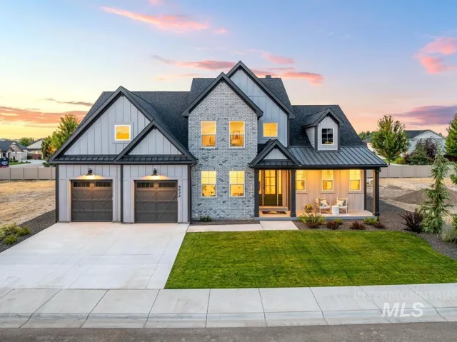 Modern farmhouse exterior with a gray brick facade, board and batten siding, a covered porch, a prominent two-car garage, and a concrete driveway