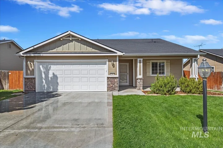 Single-story residence featuring a two-car garage, stone accent siding, and a covered entry