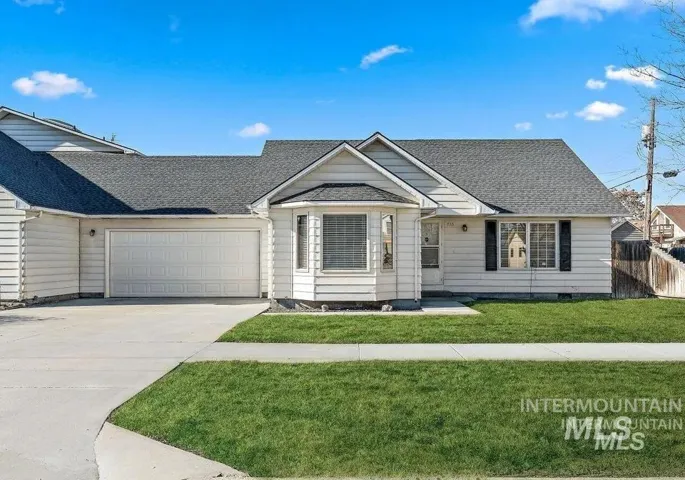 Ranch-style residence featuring white horizontal siding, a two-car garage, and a bay window