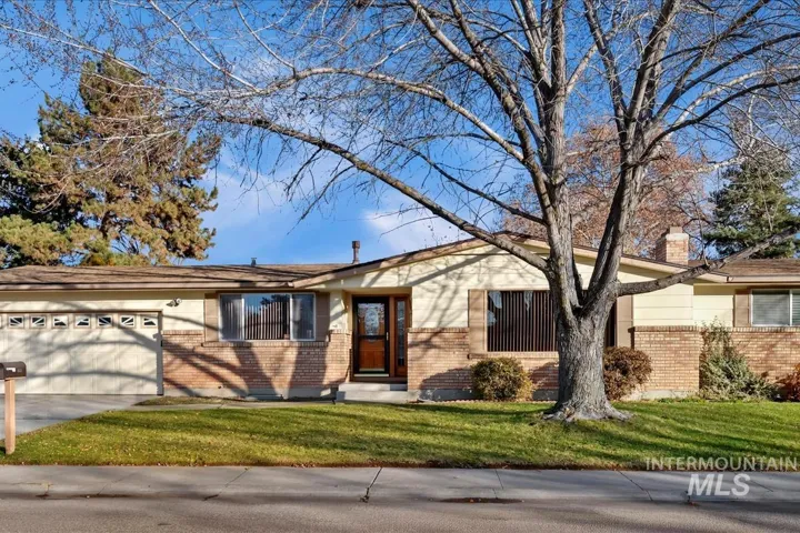 Single story home featuring brick siding, a front yard, an attached garage, and concrete driveway