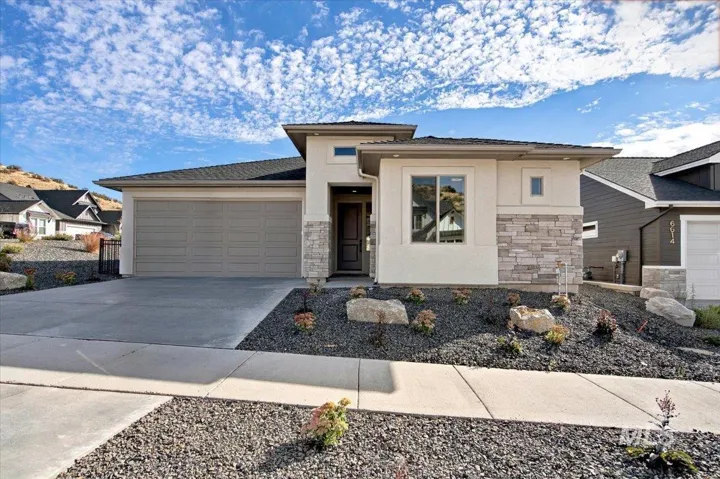 Contemporary exterior featuring smooth stucco finish, stone veneer accents, multi-level hip rooflines, and an attached two-car garage
