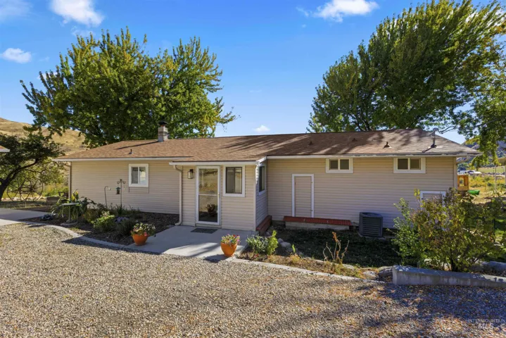 Single-story ranch exterior featuring horizontal siding, a composition shingle roof, a concrete entryway, and gravel driveway