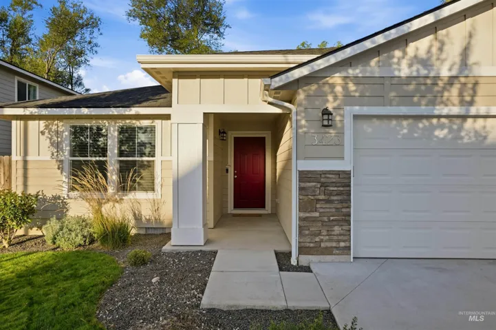 Contemporary exterior featuring stone accents, a red entry door, an attached garage, and a concrete walkway