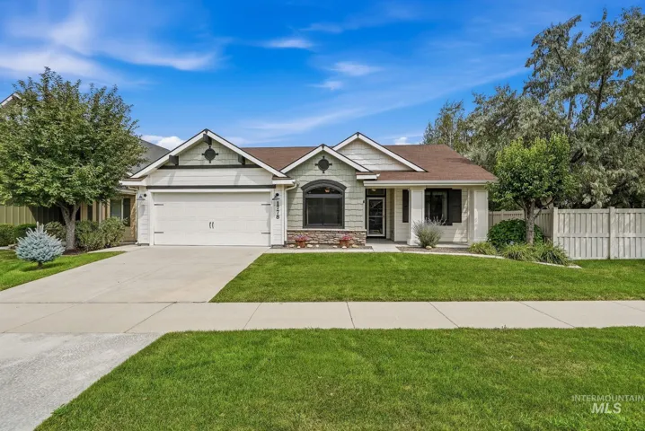 Single-story residence featuring a two-car garage, established front landscaping, and a fenced backyard