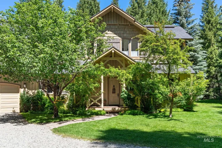 Gabled architectural style with shake siding, a covered entry, an attached garage, a gravel driveway, and mature landscaping