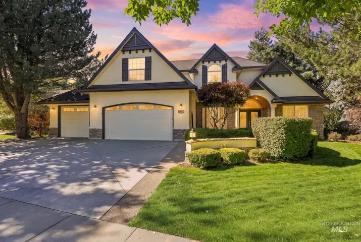 Stucco and stone exterior with arched entryways, two attached garages, and established landscaping