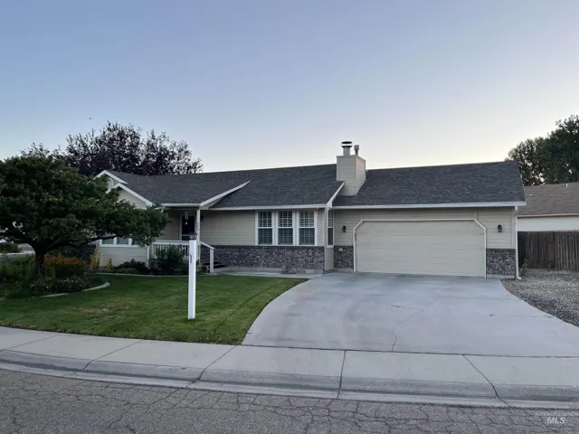 Ranch-style residence featuring a combination of siding and stone veneer, a covered entry, a two-car garage, a concrete driveway, and a front lawn with mature landscaping