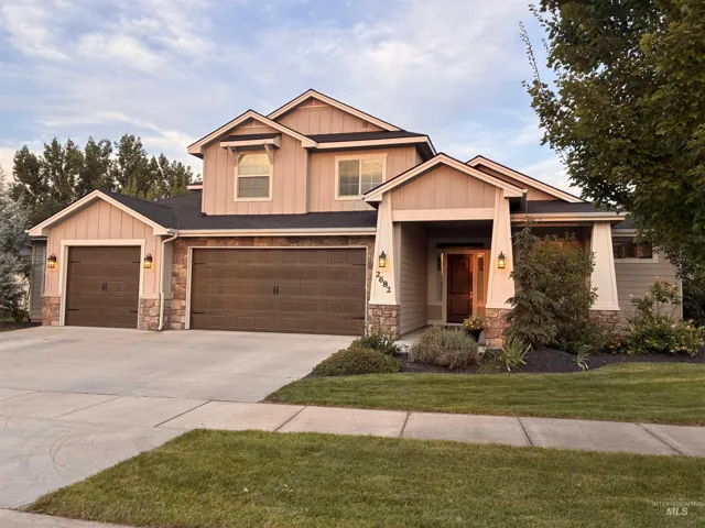 Contemporary residence featuring a covered entry, stone column accents, and a two-car garage with carriage-style doors